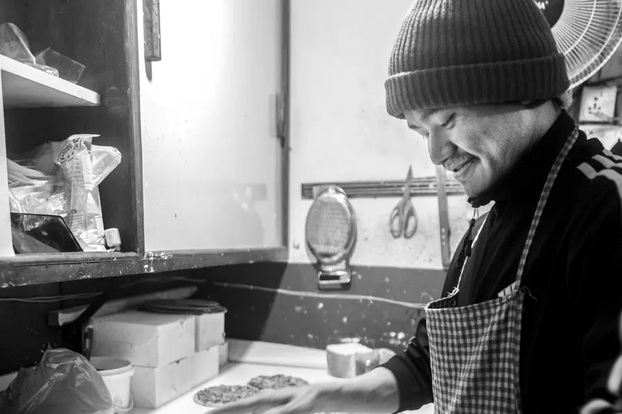 A baker in Kathmandu smiling as he wraps a tray of fresh bread for sale