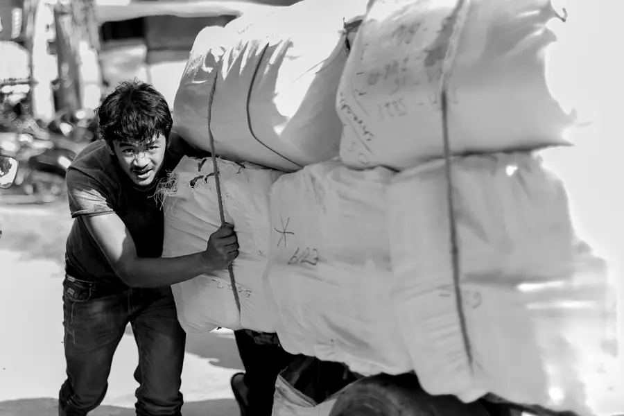 A porter in Lalitpur pushing a cart of wholesale bales, each marked with a handwritten lot number