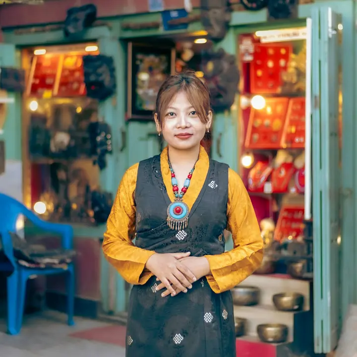 A shopkeeper in traditional dress standing at the door of her gift shop in Patan