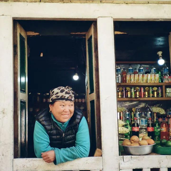 A shopkeeper smiling from the window of her small general store in Namche, Nepal