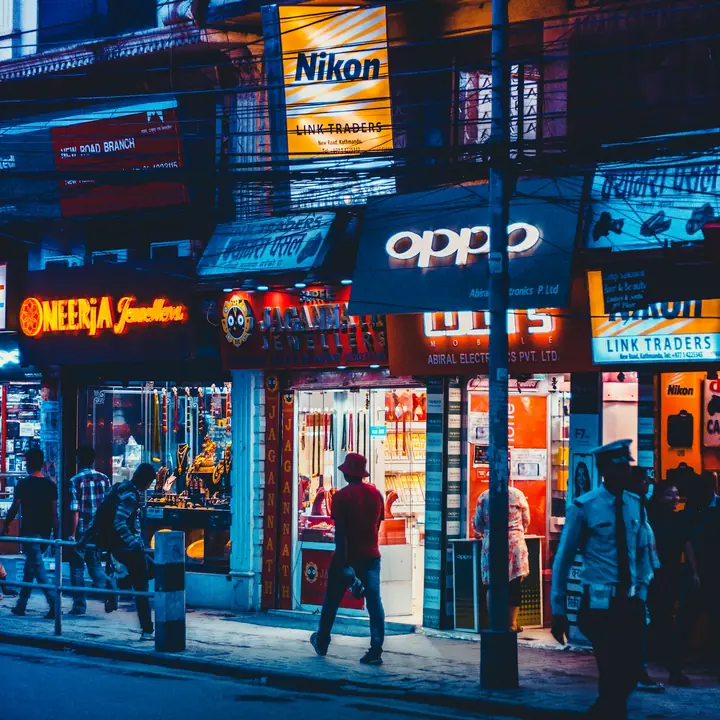 Lit-up mobile phone and electronics shops on New Road, Kathmandu, at dusk