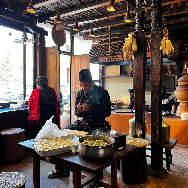 A cook preparing food at a table inside a traditional eatery in Bhaktapur